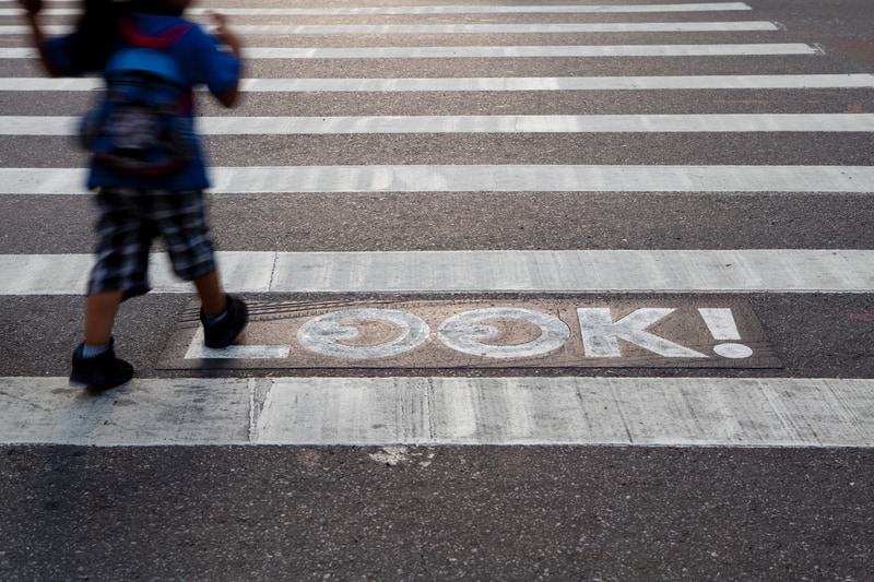 LOOK street signage painted on the road with a child crossing