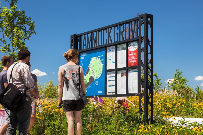 Wayfinding sign with woman reading information at Hammock Grove on Governors Island in New York Harbor